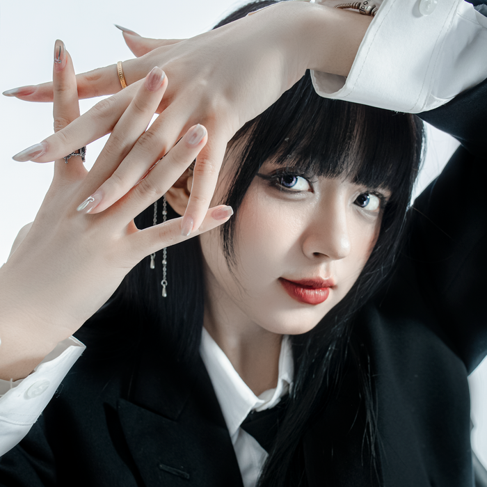 Elegant young Asian woman posing creatively in a studio, showcasing modern fashion.